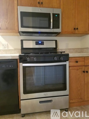 A kitchen with a black oven, a stainless steel microwave above it, and a black dishwasher to the left.