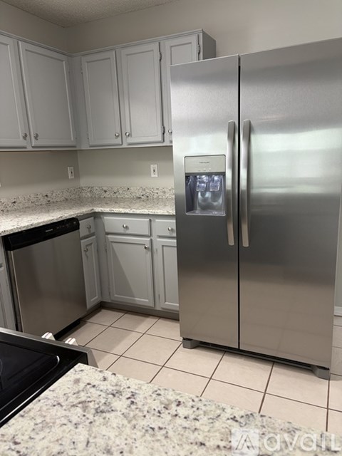 A kitchen with a granite counter top and a stainless steel refrigerator.