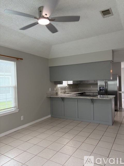 A kitchen with a fan on the ceiling and a counter with a sink.