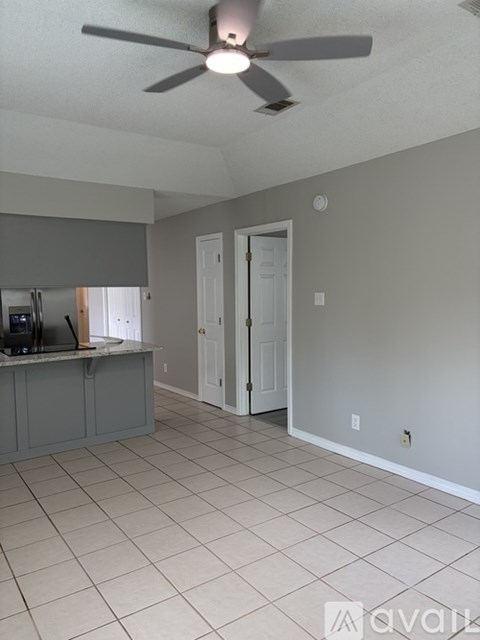 A room with a ceiling fan and tile flooring.