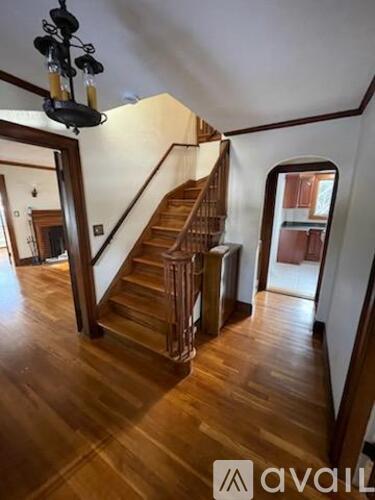 A wooden staircase with a chandelier hanging from the ceiling.