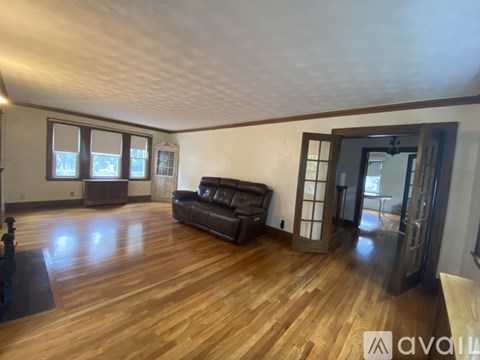 A living room with a brown couch and wooden floors.