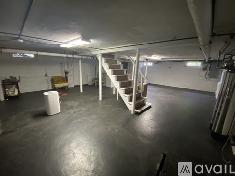 A spacious basement with a staircase and a trash bin.
