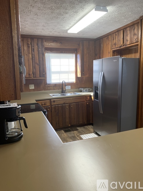 A kitchen with wooden cabinets and a black fridge.