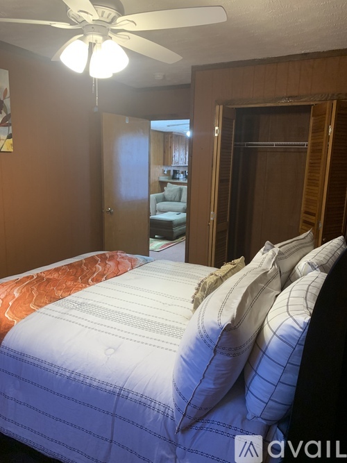 A bedroom with a bed, pillows, and a ceiling fan.