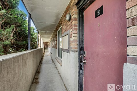 A red door with a number 2 on it is on the right side of a concrete path.