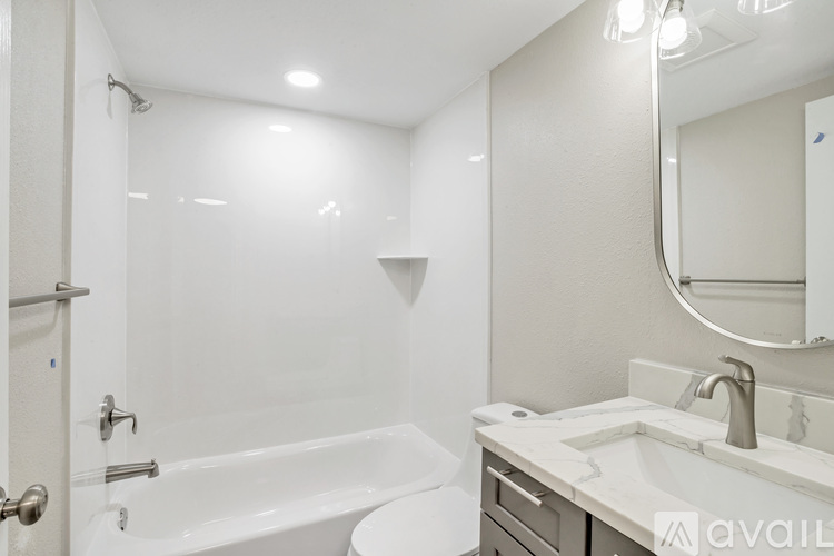 A white bathroom with a tub, sink, and mirror.