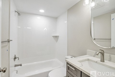 A white bathroom with a tub, sink, and mirror.