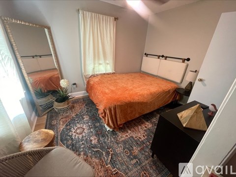 A bedroom with a bed, a chair, and a rug.