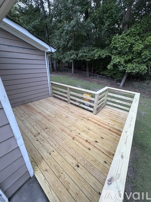 A wooden deck with a railing and a tree in the background.
