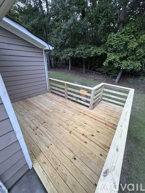 A wooden deck with a railing and a tree in the background.