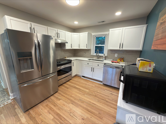 A kitchen with a stainless steel refrigerator and wooden floors.