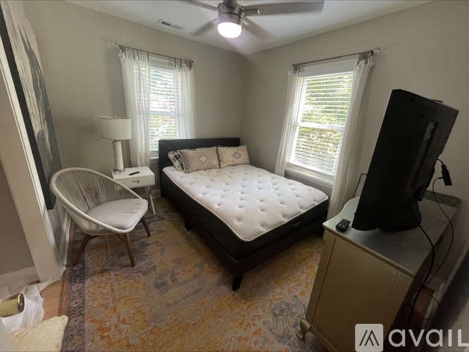 A bedroom with a bed, chair, and television.