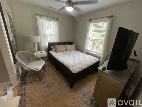A bedroom with a bed, chair, and television.