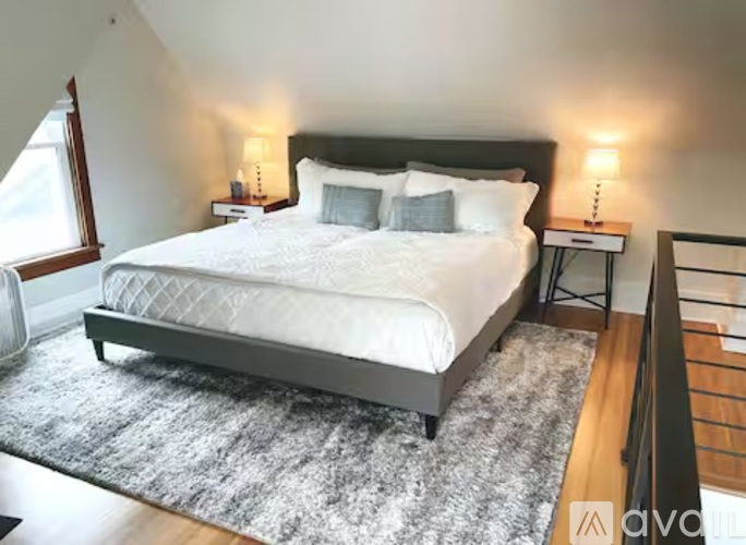 A bedroom with a large bed and a grey rug.