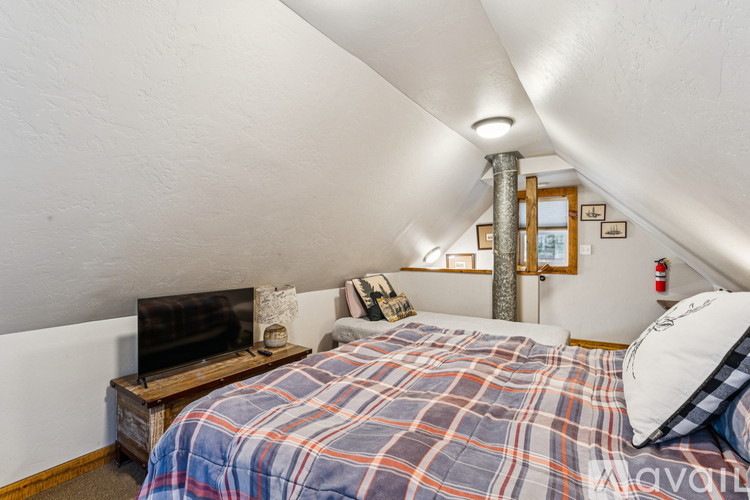 A bedroom with a bed, a television, and a fire extinguisher on the wall.