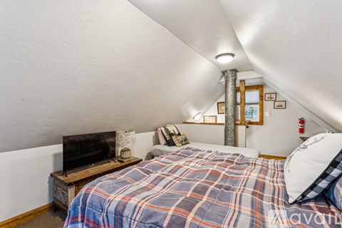 A bedroom with a bed, a television, and a fire extinguisher on the wall.
