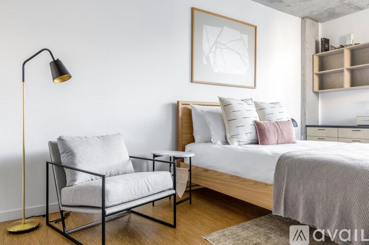 A modern bedroom with a bed, chair, and lamp.