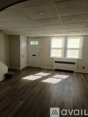 A room with wooden floors and a window with sunlight coming through.