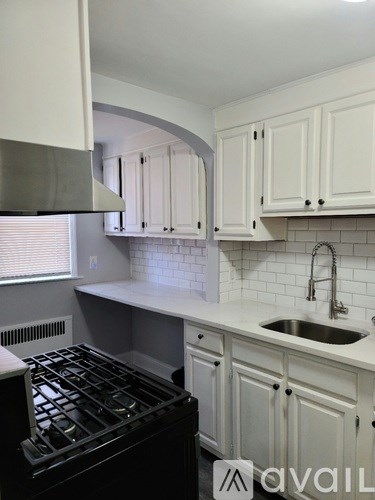 A kitchen with white cabinets and a black stove top.