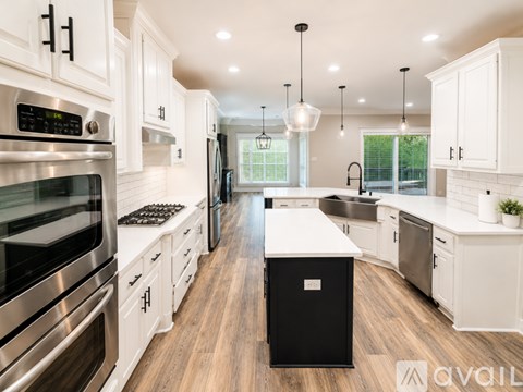 A modern kitchen with white cabinets and stainless steel appliances.