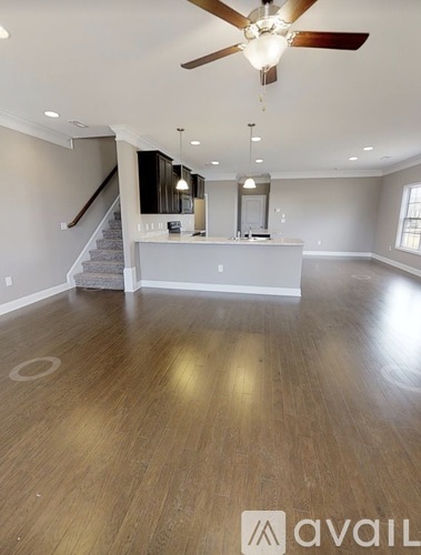 A spacious room with a ceiling fan and a staircase.