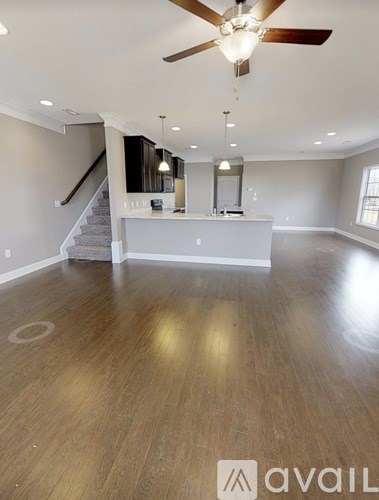 A spacious room with a ceiling fan and a staircase.
