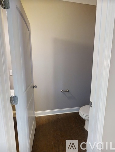 A white door is open to a bathroom with a toilet.