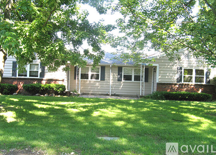 A house with a green lawn and trees in front.
