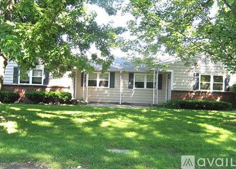 A house with a green lawn and trees in front.