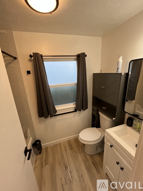 A bathroom with a toilet, sink, and window.
