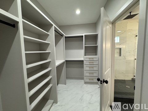 A spacious walk-in closet with white shelving and drawers.