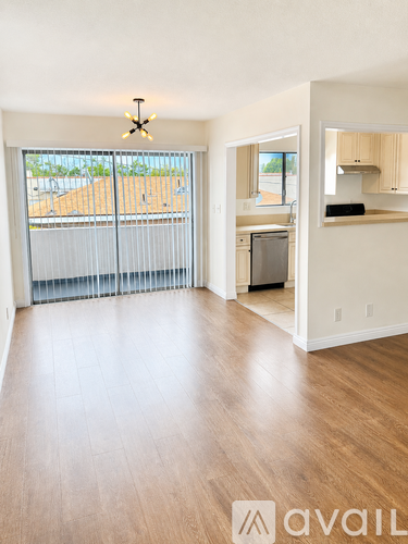 A large empty room with wooden floors and a balcony with a view of a construction site.