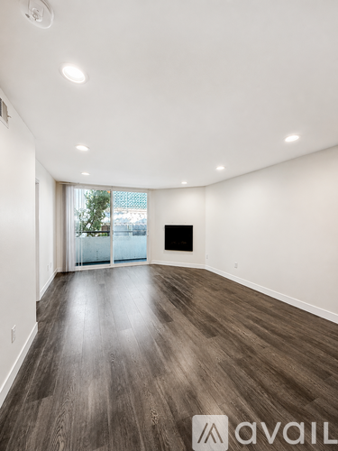 A spacious room with wooden flooring and a large window.