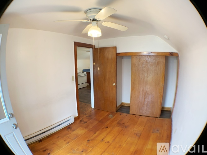 A room with a ceiling fan and wooden floors.