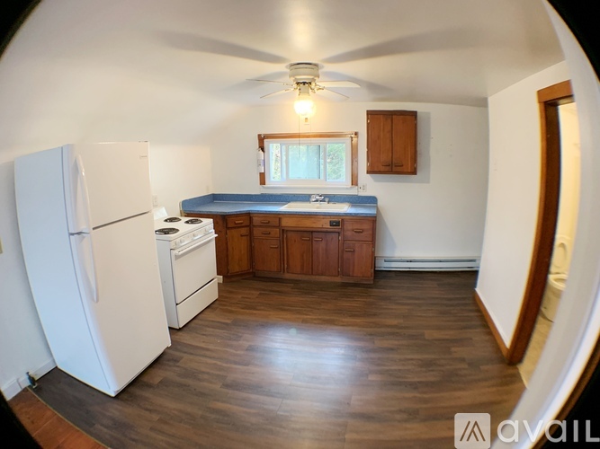 A kitchen with a white refrigerator and wooden floors.