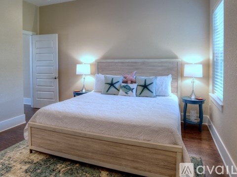 A bedroom with a large bed and two lamps.