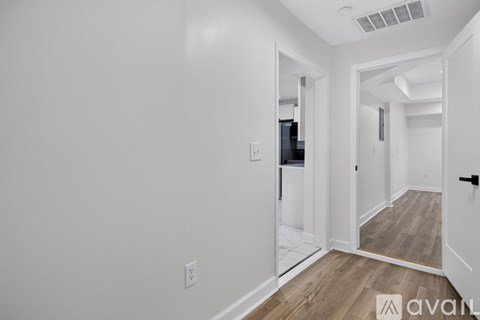 A hallway with a white door and a black handle.