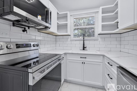 A kitchen with white cabinets and a black stove top oven.
