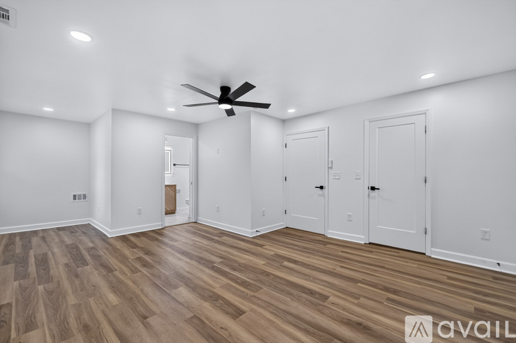 A spacious room with wooden flooring and a ceiling fan.