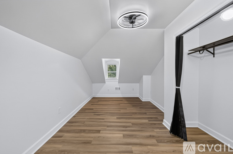 A room with wooden flooring and a window with a view of trees.