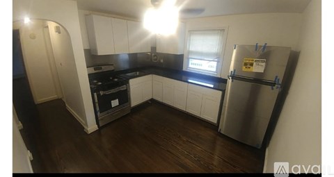 A kitchen with a stainless steel refrigerator and wooden floors.