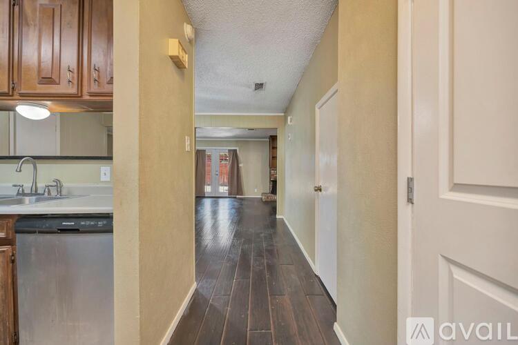 A long hallway with a kitchen area on the left and a door on the right.