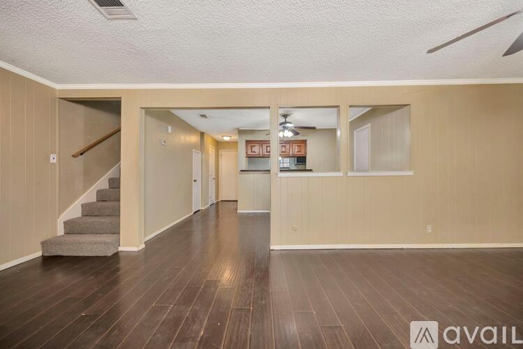 A spacious room with wooden floors and a staircase leading to another level.