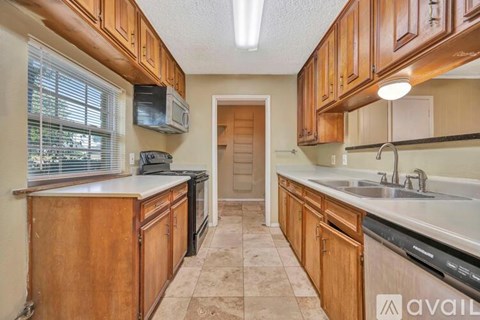 A kitchen with wooden cabinets and a tiled floor.