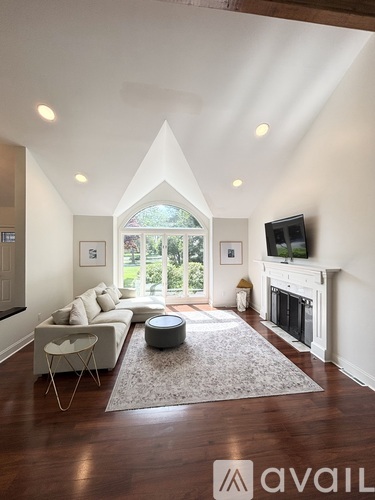 A living room with a white couch, a fireplace, and a television.