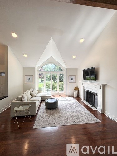 A living room with a white couch, a fireplace, and a television.
