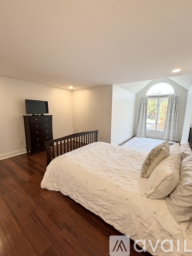 A bedroom with a large bed and a TV on a cabinet.