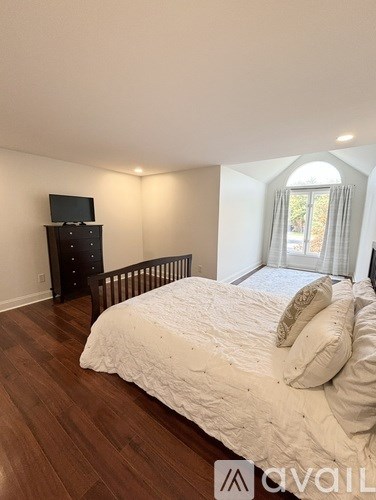 A bedroom with a large bed and a TV on a cabinet.