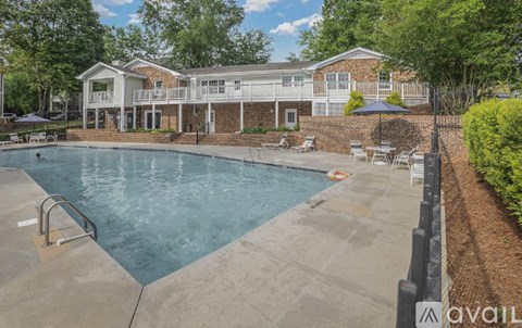 A large outdoor swimming pool surrounded by a patio area with a building in the background.